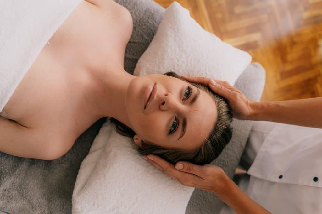 Woman lying on bed having an acupuncture on her face