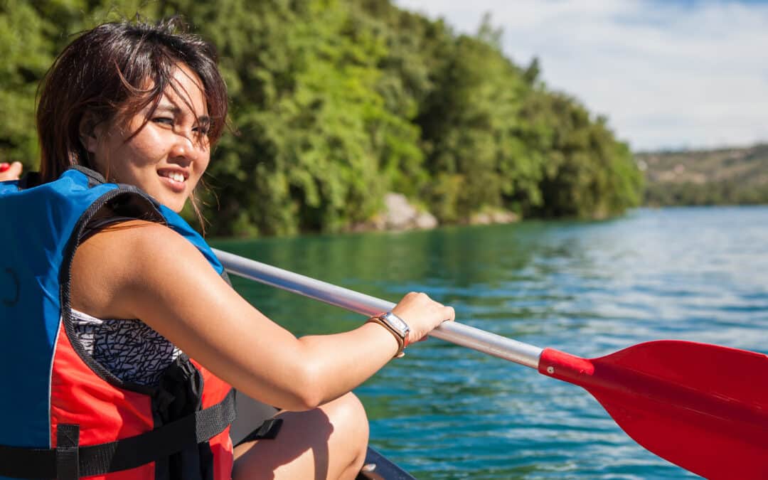 Pretty, young woman on a canoe on a lake, paddling, enjoying a l