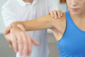 Physical therapist examines the shoulder of woman